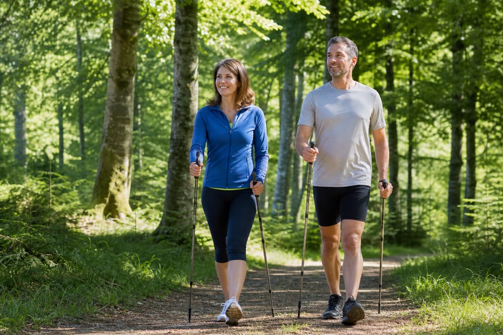 Deux personnes pratiquent la marche nordique sur un sentier forestier